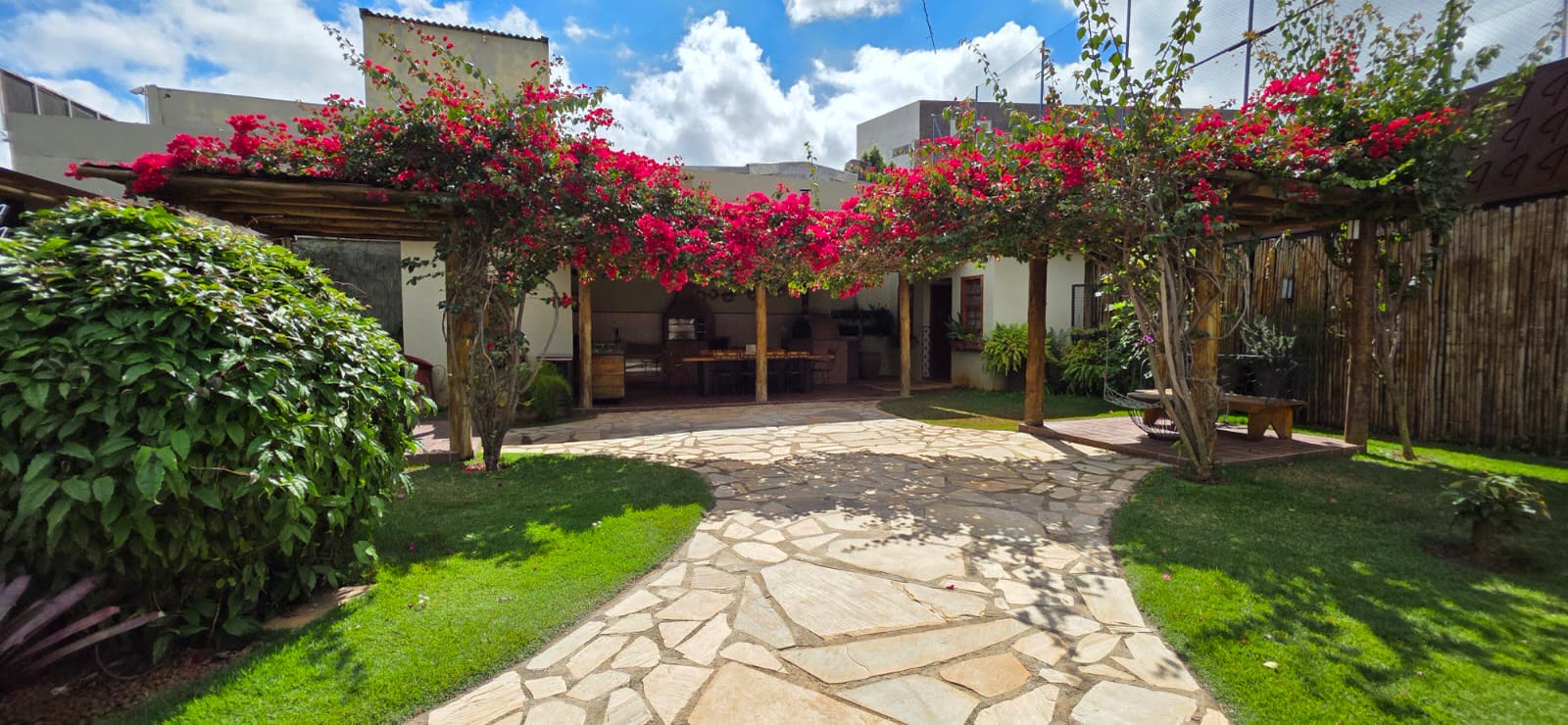 Jardim do Intimista com pergolado tomado por Bougainvillea florida e caminho de pedra