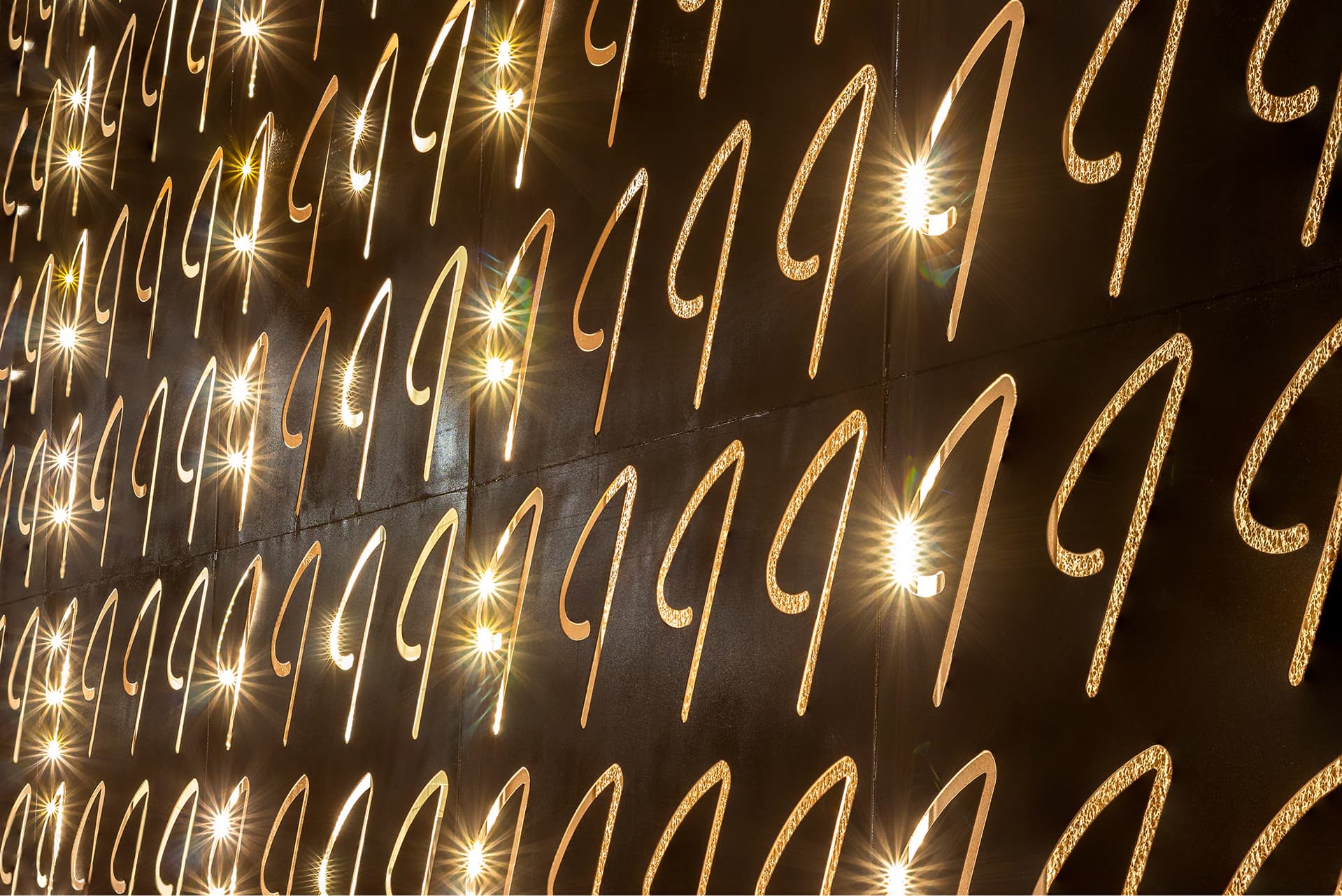 Painel de aço vazado com o símbolo do Intimista, iluminado por trás à noite